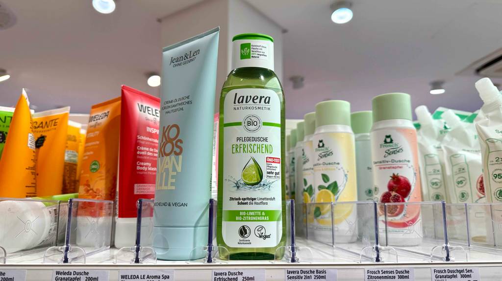 Eine transparente Quetschflasche mit getestetem Lavera-Duschgel steht auf einem Regal mit Hautpflegeprodukten im Drogeriemarkt.