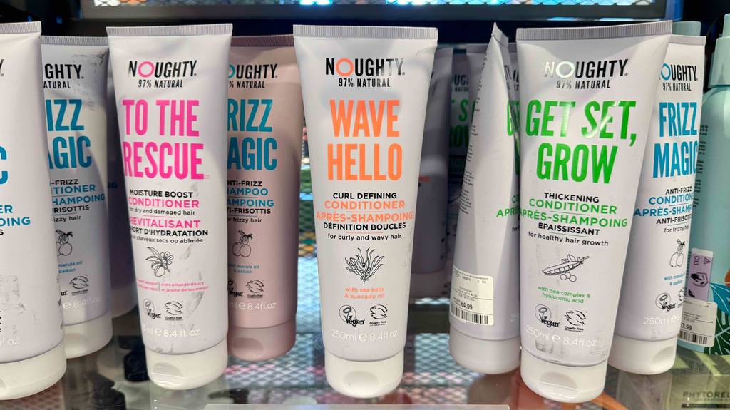Mehrere Tuben mit getestetem Locken-Conditioner stehen nebeneinander auf einem Verkaufsregal.