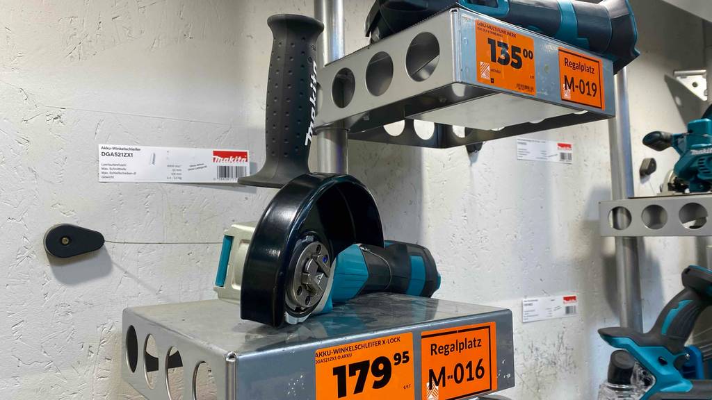 Makita-Akku-Winkelschleifer im Test: ein türkis-schwarzes Modell inklusive Soft-Griff liegt auf einem Ausstellungsregal mit orangefarbenem Preisschild.