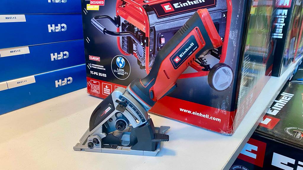 Mini-Handkreissäge-Test: Seitenansicht auf ein grau-rotes Einhell-Modell mit montiertem Parallelanschlag vor einer Originalverpackung von einem Einhell-Generator.