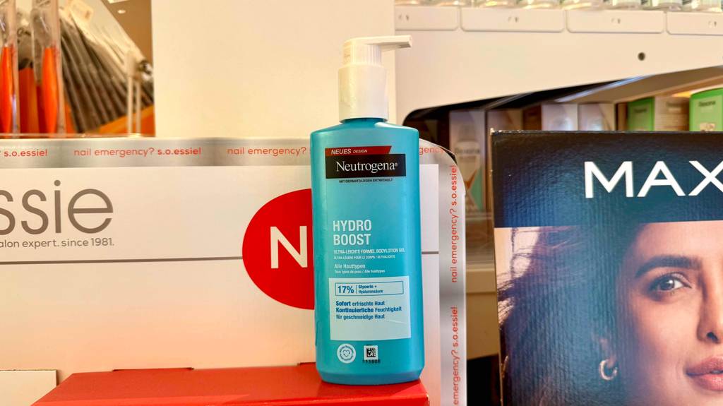 Im Test: Neutrogena-Bodylotion im blauen Spender steht auf einem roten Karton im Drogeriemarkt.