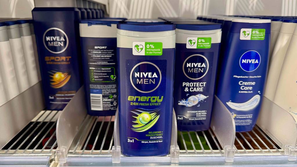 Mehrere dunkelblaue Quetschflaschen mit getestetem Nivea-Duschgel Männer des Typs Energy stehen auf einem Regal im Drogeriemarkt.