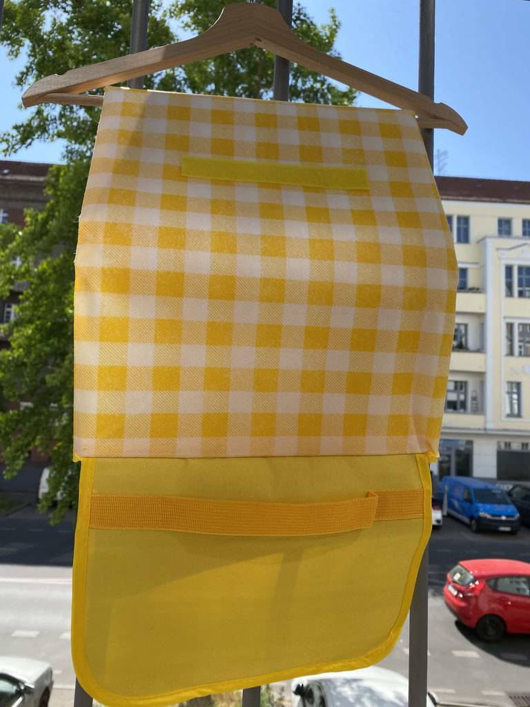 Gelb-weiß-karierte getestete Picknickdecke hängt über einem Bügel im Außenbereich.