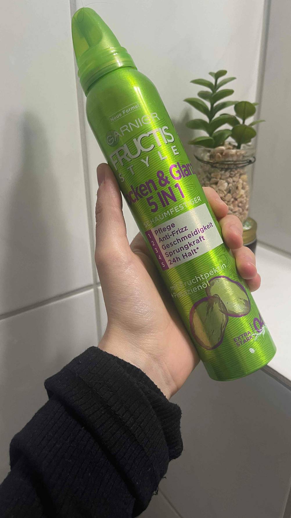 Im Test: Der Schaumfestiger für Locken befindet sich im giftgrünen Spender in einer Hand.