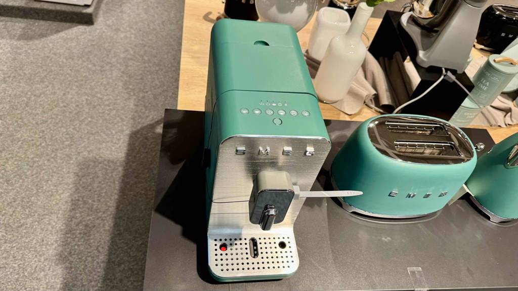Der getestete schmale Kaffeevollautomat im mintgrünen Design steht von oben betrachtet auf einer Ausstellungsfläche im Geschäft.