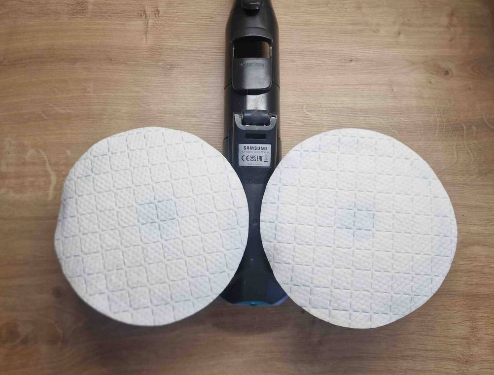 Sprühwischer-Test: Detailansicht zweier Wischmopp-Köpfe inklusive weißer Wisch-Pads auf einem Holzboden.