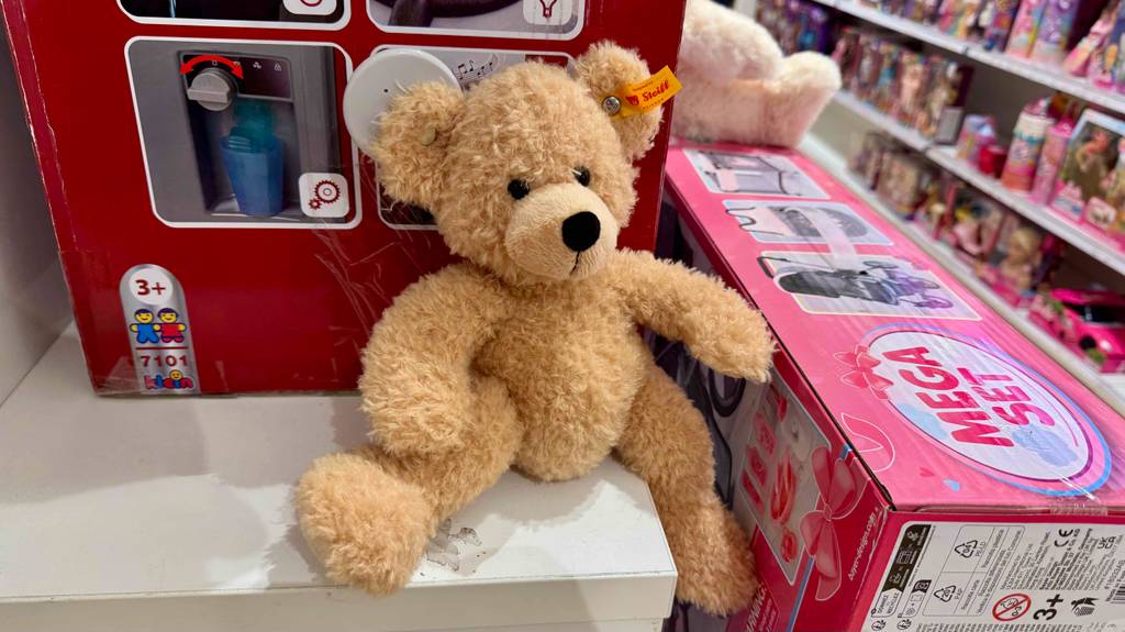 Der getestete Steiff-Teddy sitzt auf einem Spielzeug-Regal im Geschäft.