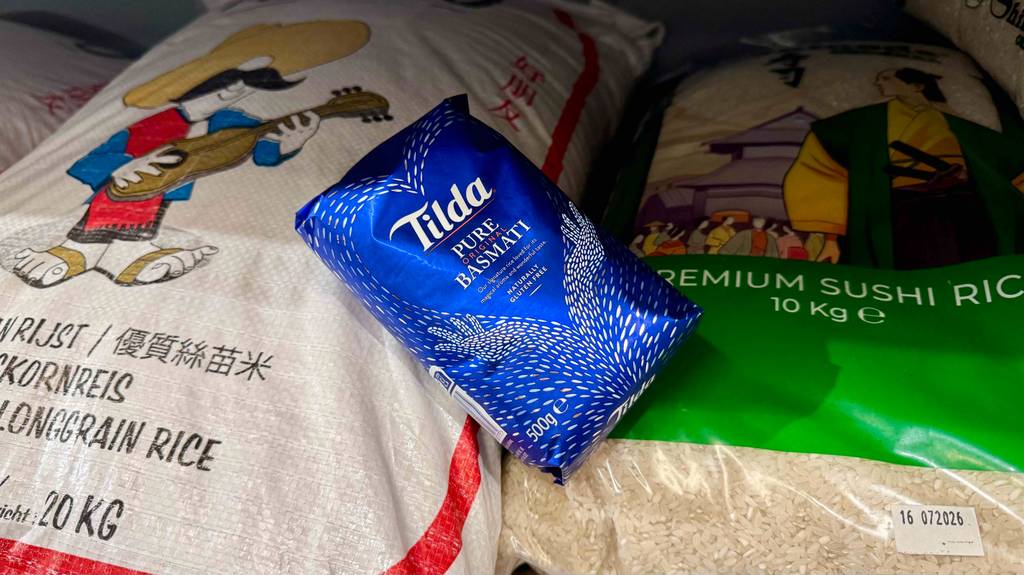 Eine blaue 500-g-Packung mit getestetem Tilda-Reis liegt auf Säcken mit 10 und 20 Kilogramm Reis.