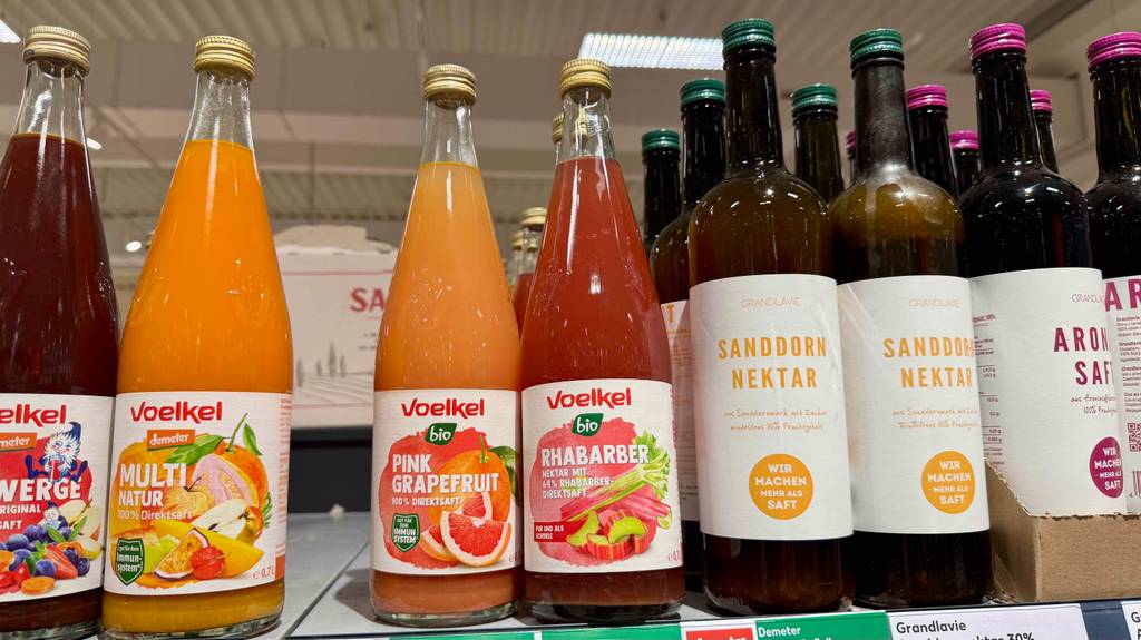 Im Test: Voelkel-Saft in mehreren Glasflaschen befindet sich auf einem Regal im Supermarkt neben anderen Säften.