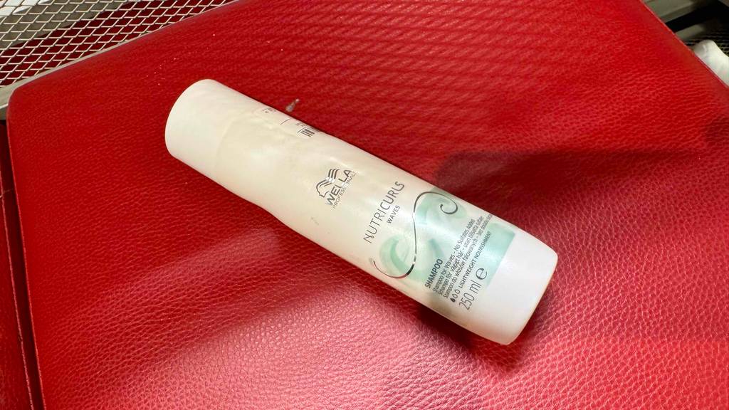 Getestet: Ein Wella-Shampoo in der weißen Kunststoffflasche liegt auf einem roten Lederbezug.