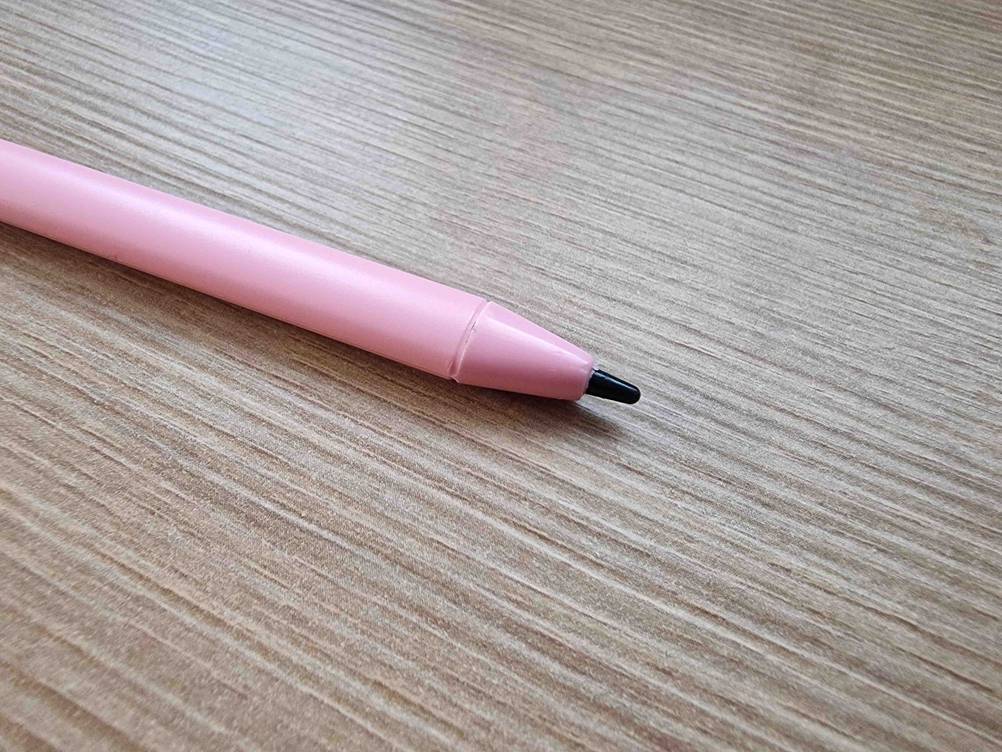 Zaubertafel im Test: Rosa Stift inklusive schwarzer Spitze liegt auf einem gemaserten Untergrund.