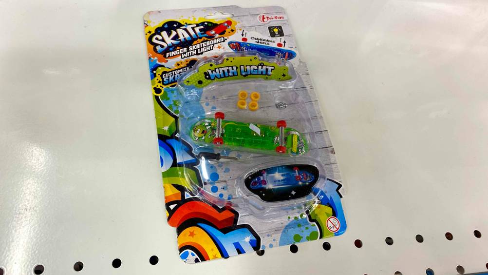 Getestetes Finger-Skateboard befindet sich in seiner transparenten Originalverpackung auf einem hellen Regal.