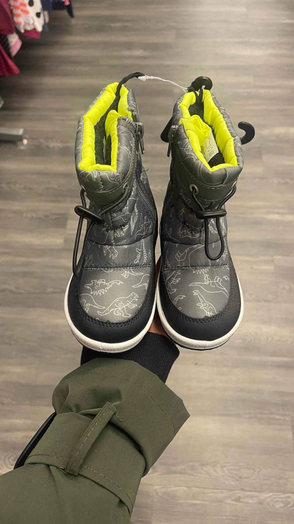 Im Test: Die Kleinkinder-Winterstiefel in Grau stehen auf einer Handfläche im Geschäft.