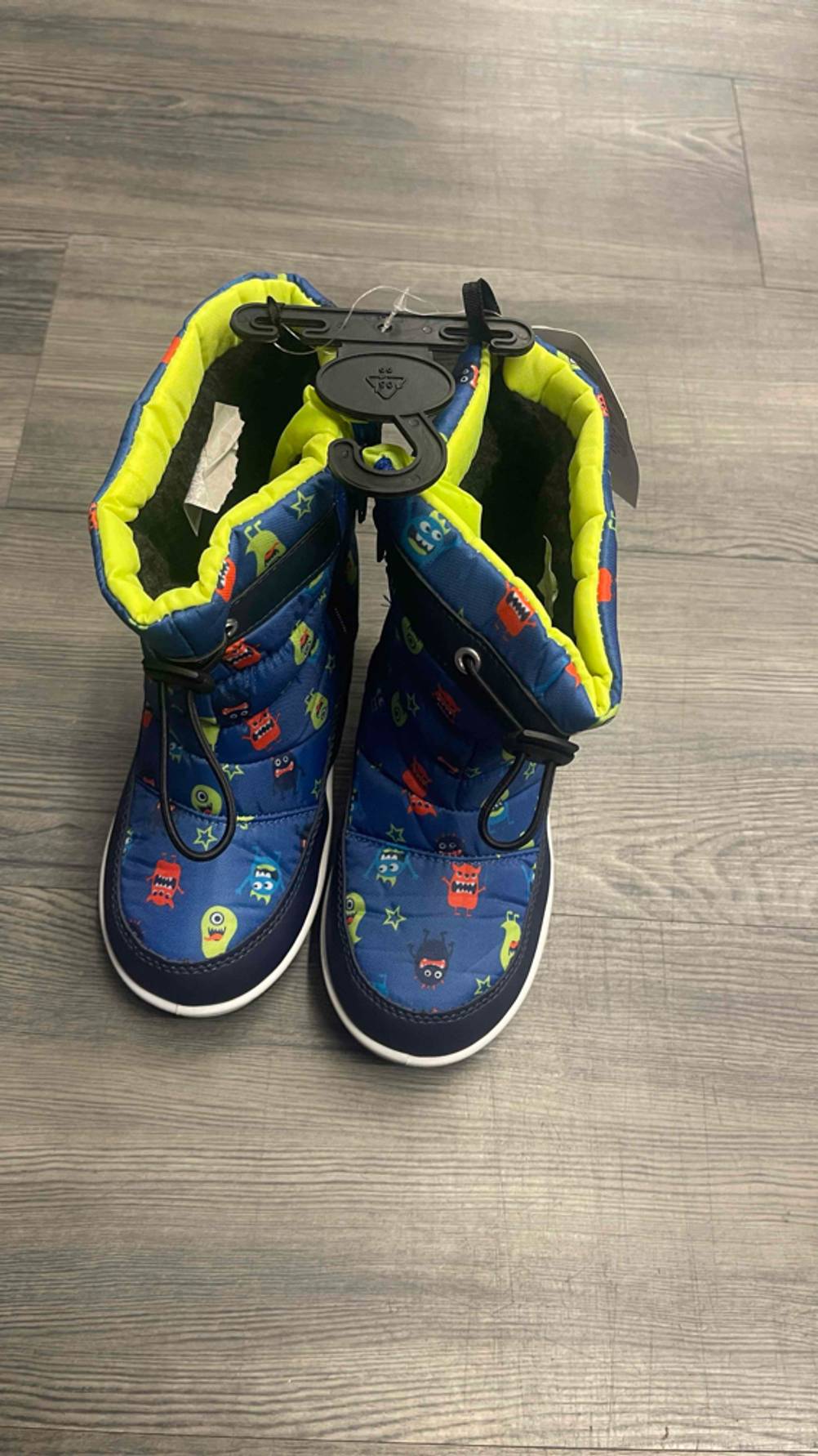 Ein Paar blaue Winterstiefel für Kleinkinder im Test stehen auf einer Holzfläche im Geschäft.