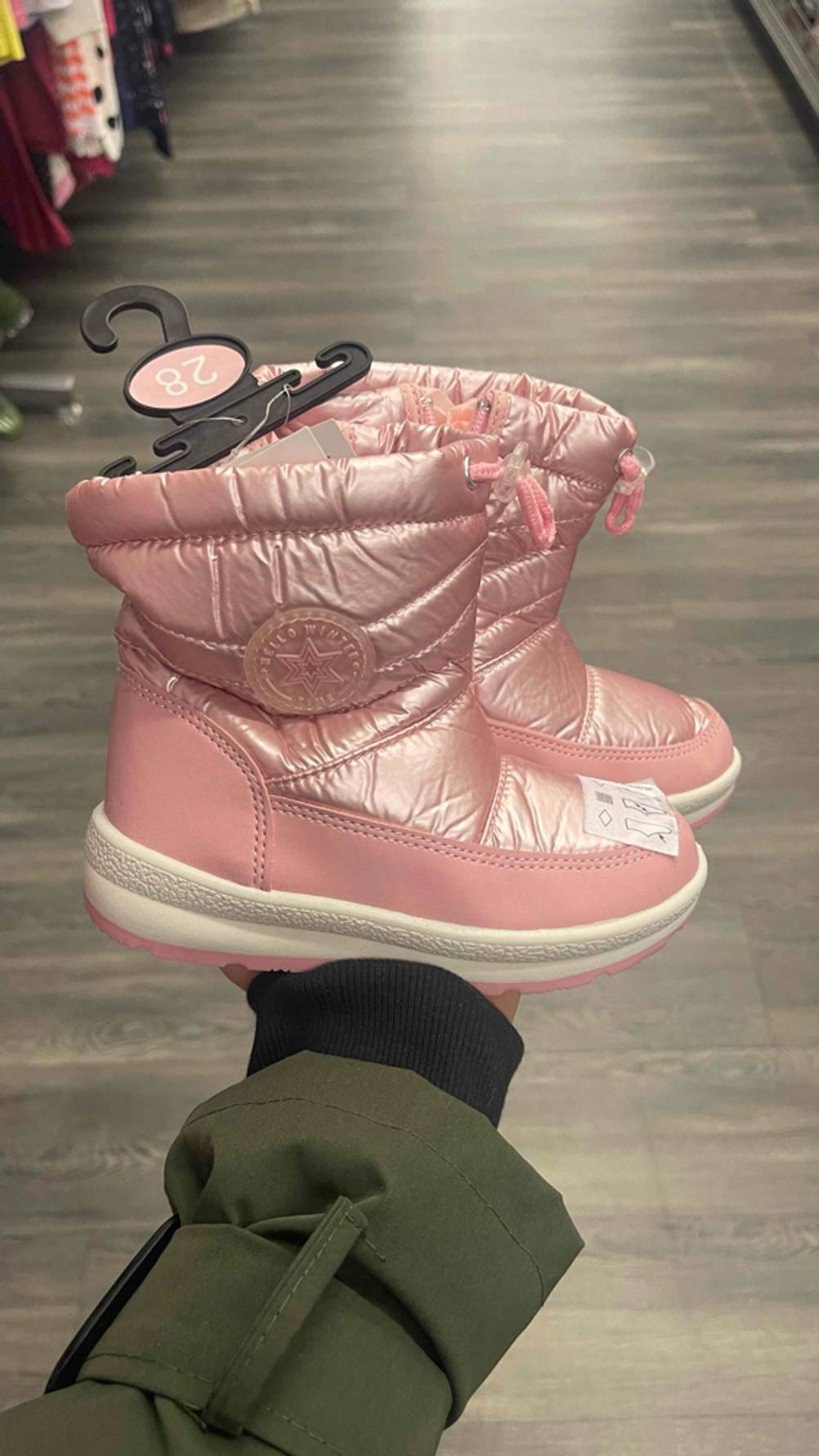 Die rosafarbenen Kleinkinder-Winterstiefel im Test stehen seitlich auf einer Handfläche im Geschäft.