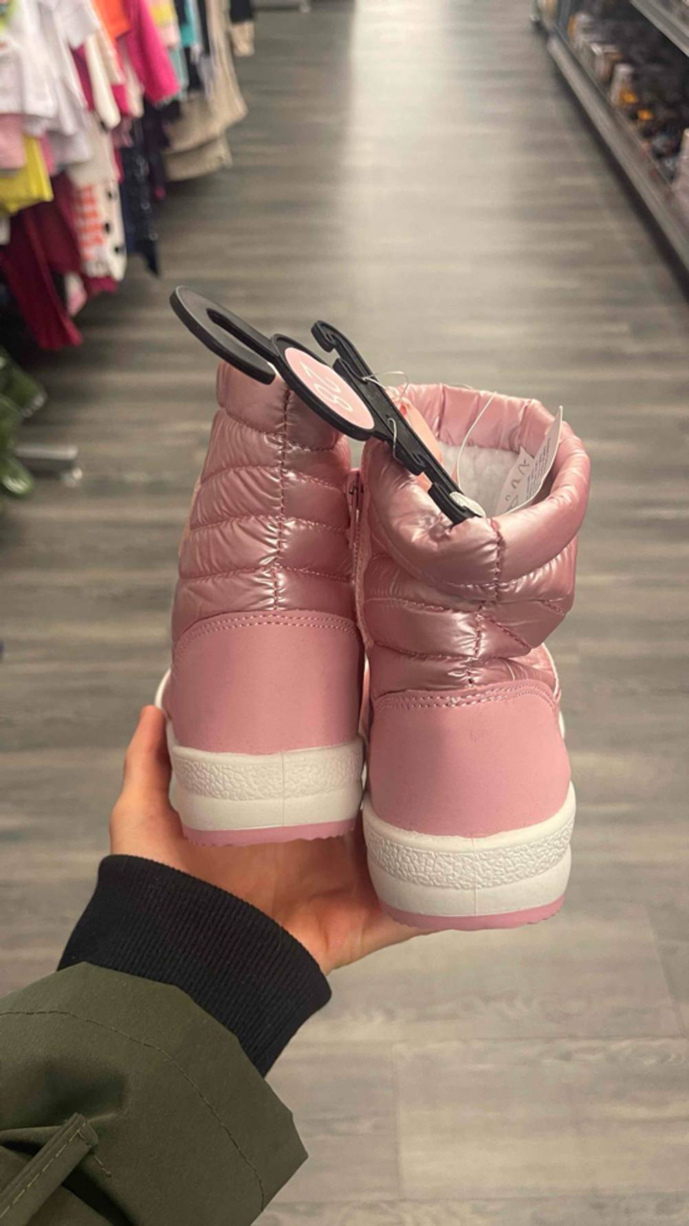 Eine Hand hält die getesteten Winterstiefel für Kleinkinder in der Farbe Rosa mit dem Fersenbereich in die Kamera.