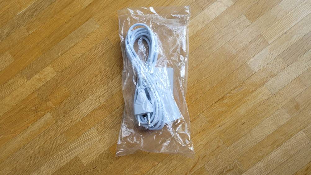 Ein transparent verpacktes Verlängerungskabel im Test auf einem Holzboden.