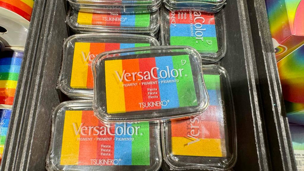 Mehrere Stempelkissen im Test mit fünf verschiedenen Farben liegen übereinander in einem Verkaufsbehälter.