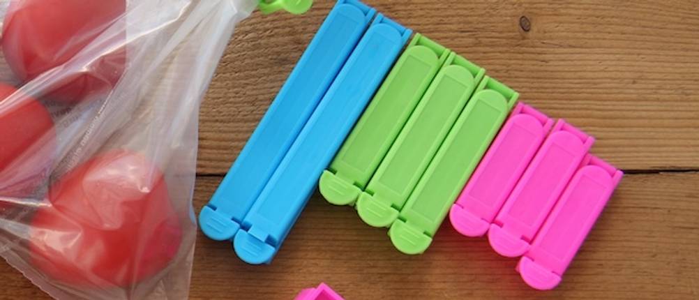 Bunte getestete Verschlussclips nebeneinander auf einem Holzbrett in Großaufnahme.