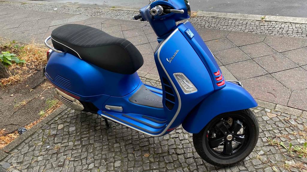 Im Test: Ein blauer Vespa Motorroller steht auf einer Straße.