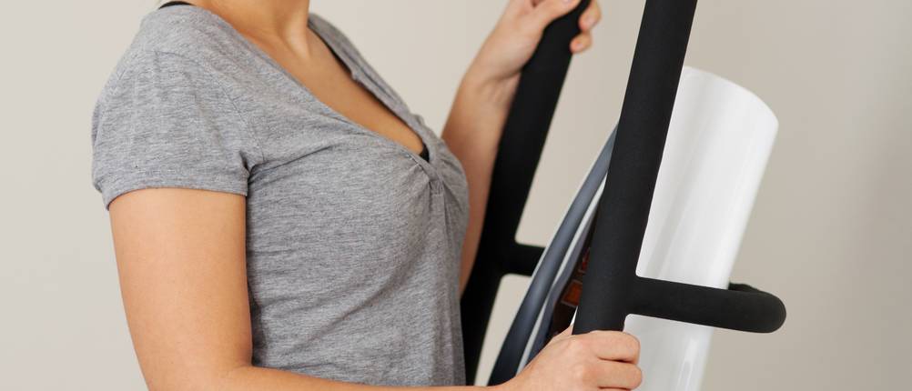 Vibrationsplatten mit Säule im Test: junge Frau, die auf einer Vibrationsplatte steht und in die Kamera lächelt