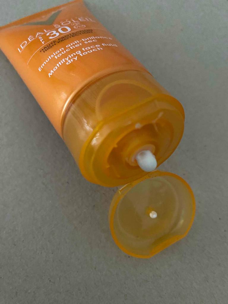 Ansicht der weißen Creme an der Quetschöffnung einer geöffneten, orangefarbenen Tube der getesteten Tagescreme mit LSF 30.