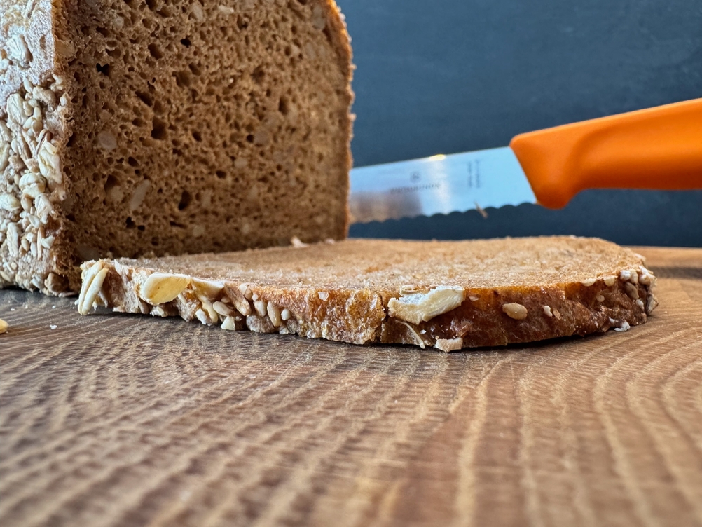 Gerade geschnittene Brotscheibe, Victorinox-Brotmesser im Hintergrund