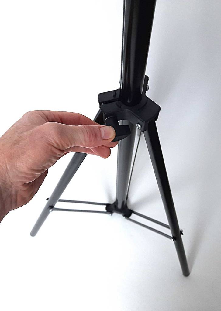 Eine Hand dreht am Einstellungsrad eines Lampenstativs im Test.