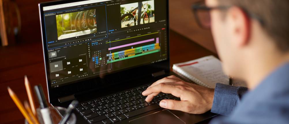 Videobearbeitungsprogramme im Test: Ein Mann mit Brille bearbeitet ein Video an seinem Laptop.