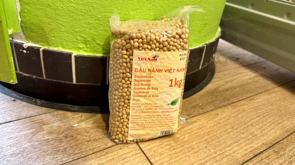 Eine Packung Sojabohnen steht zum testen vor einer grünen Wand mit schwarzem Sockel.