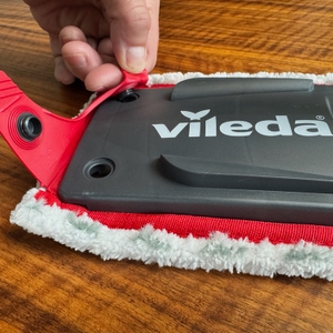 Eine Hand löst das Pad von der Halterung am Vileda 168309.