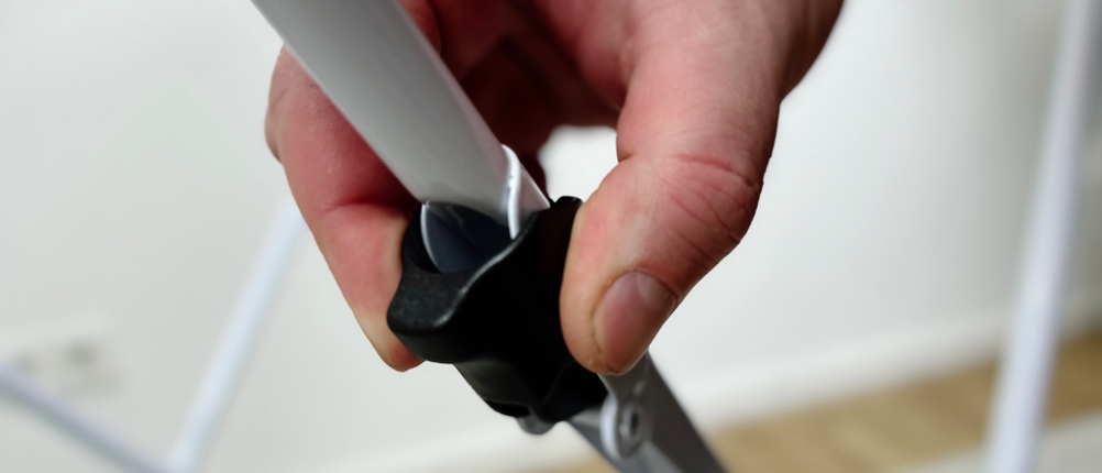 Nahaufnahme einer Hand, die den Sicherungsknopf des Vileda Doble betätigt. Der schwarze Drehverschluss fixiert eine Strebe.