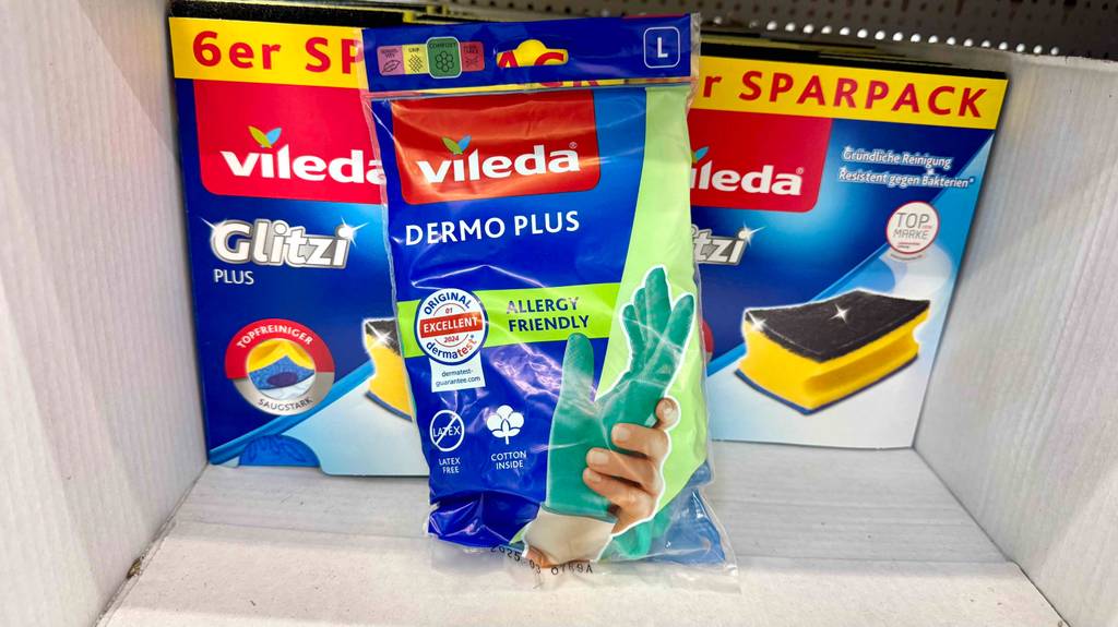Gummihandschuhe im Test: Eine Packung steht vor Spülschwämmen.