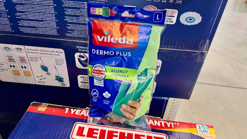 Eine Packung mit Gummihandschuhen steht zum testen vor einem verpackten Putzeimer.