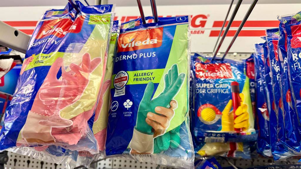 Gummihandschuhe im Test: Mehrere Packungen unterschiedlicher Sorten hängen in einem Regal.