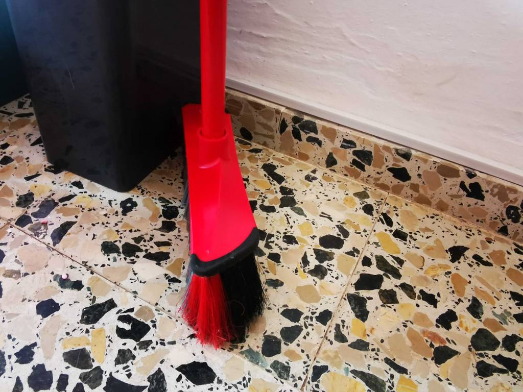 Ein getesteter Haushaltsbesen steht neben einem Mülleimer.