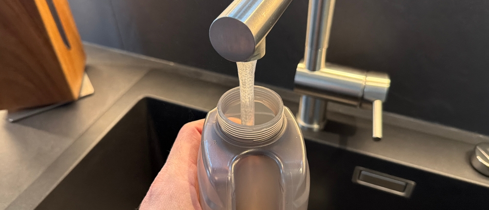 Ein Behälter vom Vileda Spray & Clean wird mit Wasser gefüllt.