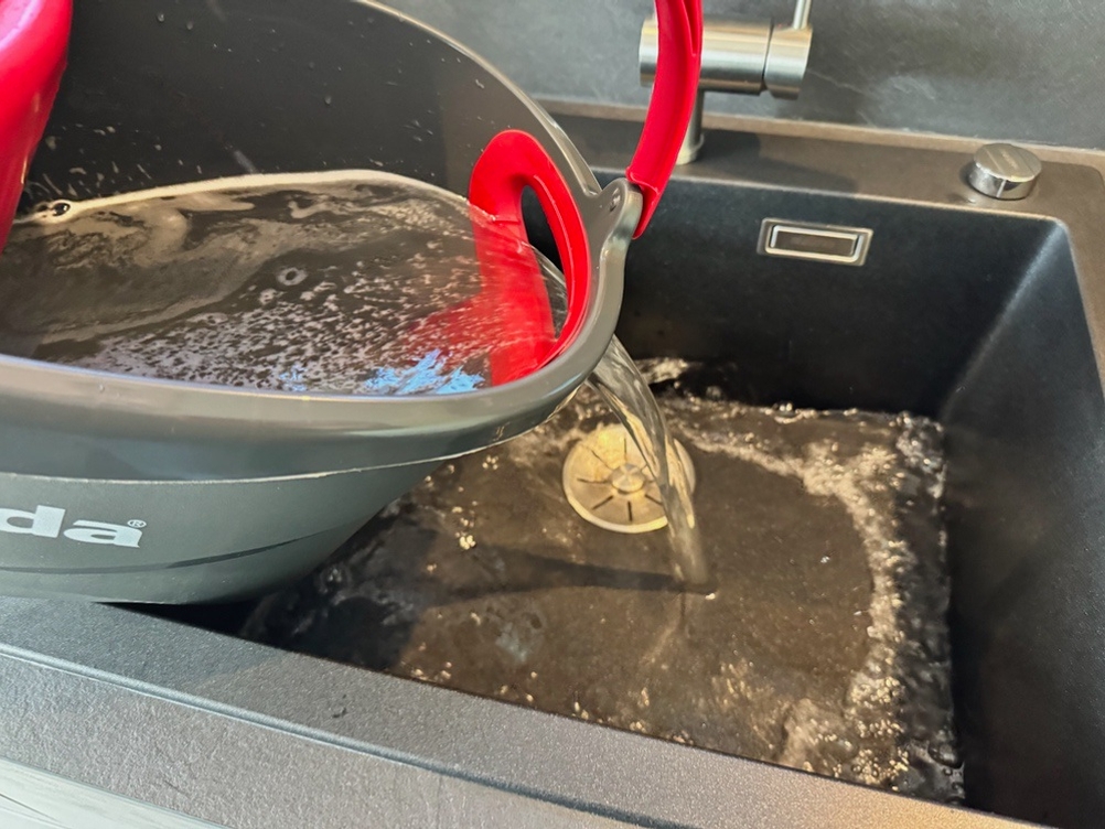 Wasser wird aus dem Behälter des Vileda-Turbo-Komplett-Bodenwischers geschüttet.