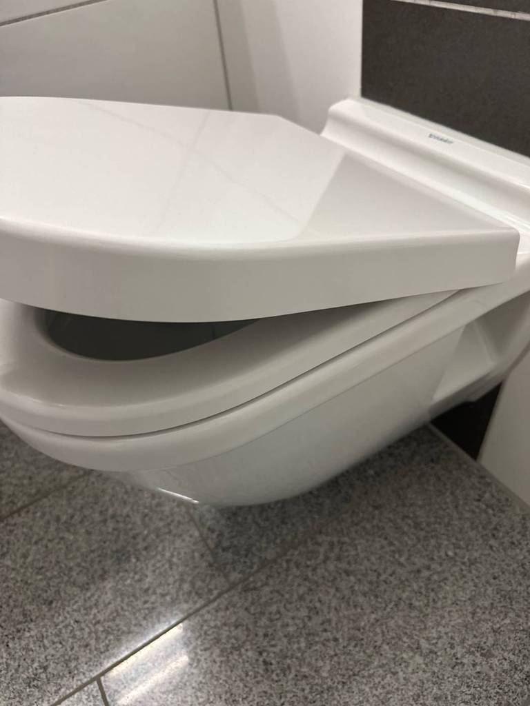 Leicht angehobener Deckel eines getesteten WC-Sitzes mit Absenkautomatik auf einer Toilette.