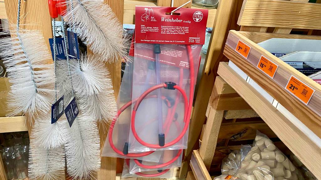 Weinheber im Test: An einem Verkaufsstand hängen neben mehreren verpackten vierteiligen Weinhebern Reinigungsbürsten zum Säubern des Inneren von Flaschen, Korken und weiteres Zubehör für die Weinabfüllung.