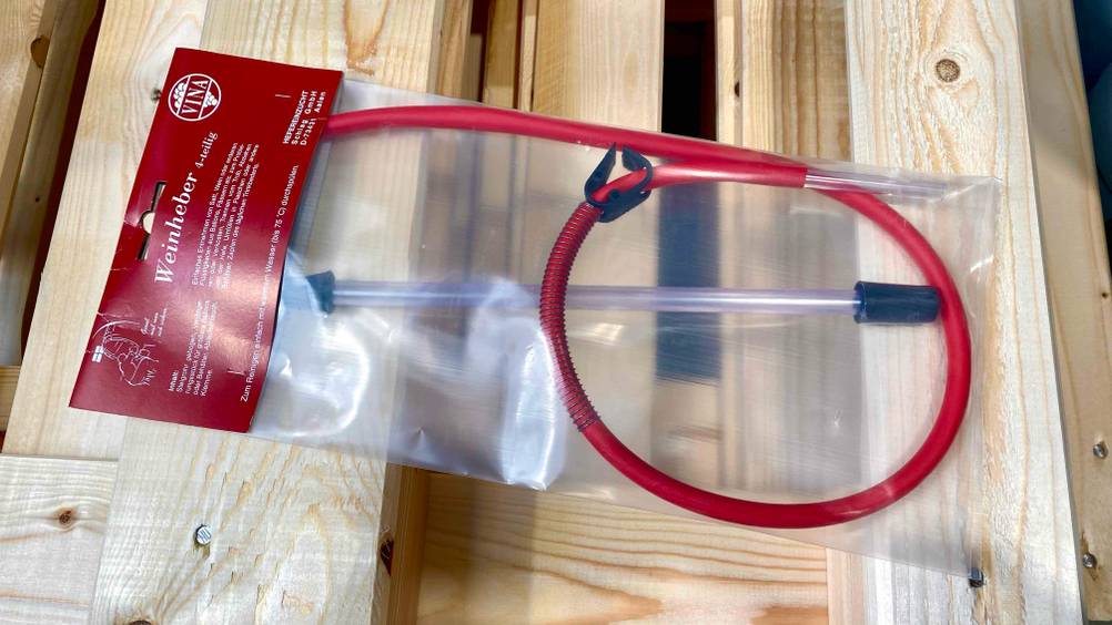 Weinheber getestet: Ein transparent verpackter Weinheber liegt auf einer Holzpalette.