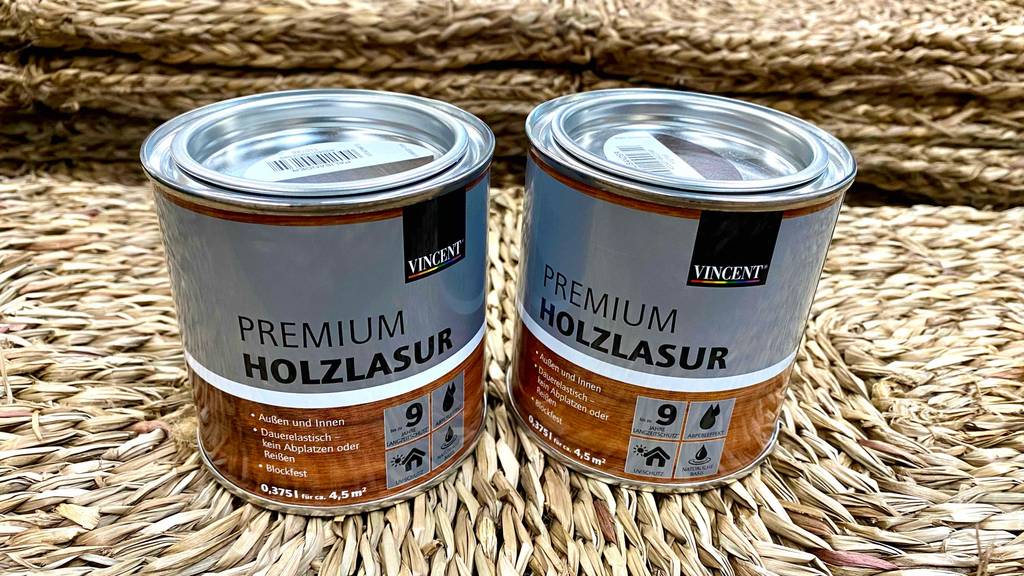 Zwei Dosen mit Vincent Premium Holzlasur im Test stehen nebeneinander auf einem Bast-Teppich.
