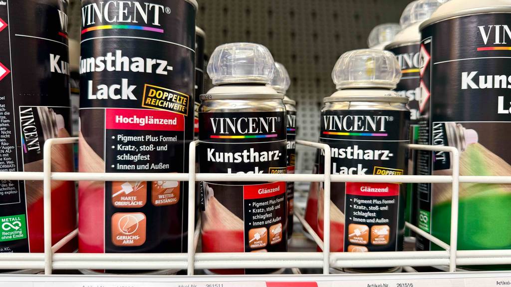 Kunstharzlack im Test: Mehrere Dosen unterschiedlicher Ausführungen stehen in einem Regal.