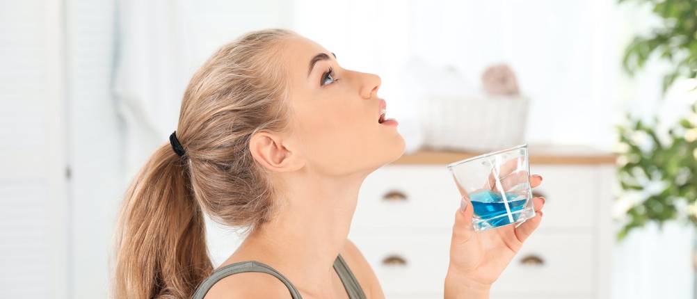 Viren-Mundspülung-Test: Eine blaue Mundspülung wird gegurgelt.