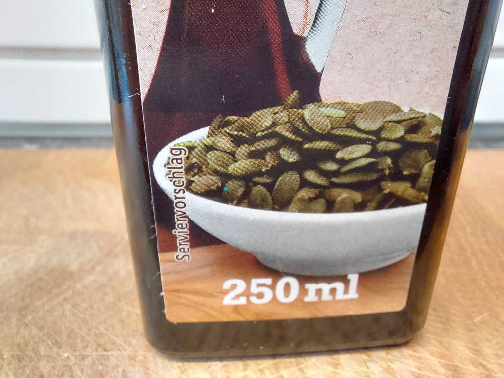 Kürbiskernöl-Test: Detailansicht einer lichtdichten 250-ml-Flasche mit Kürbiskernen auf dem Etikett.