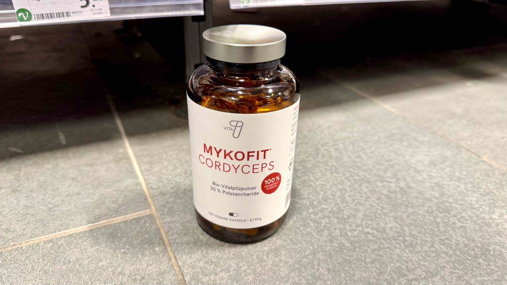 Cordyceps im Test: Eine braune Glasdose mit 180 veganen Kapseln steht vor einem Einkaufsregal.