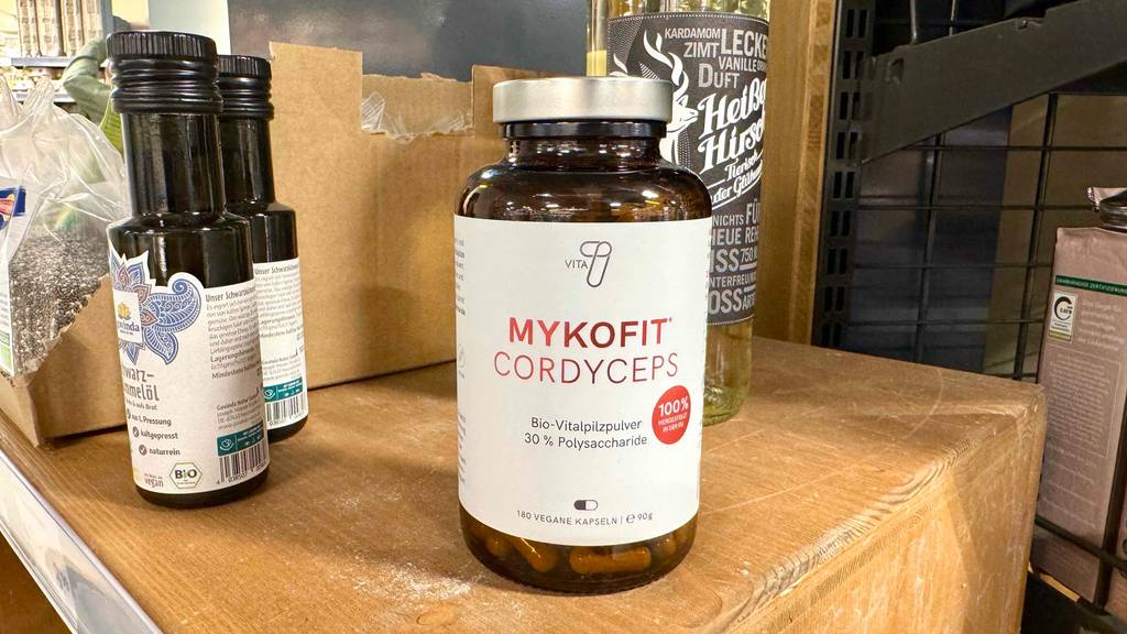 Cordyceps testen: Eine braune Glasdose mit 180 veganen Kapseln steht auf einem Holzregal im Geschäft.