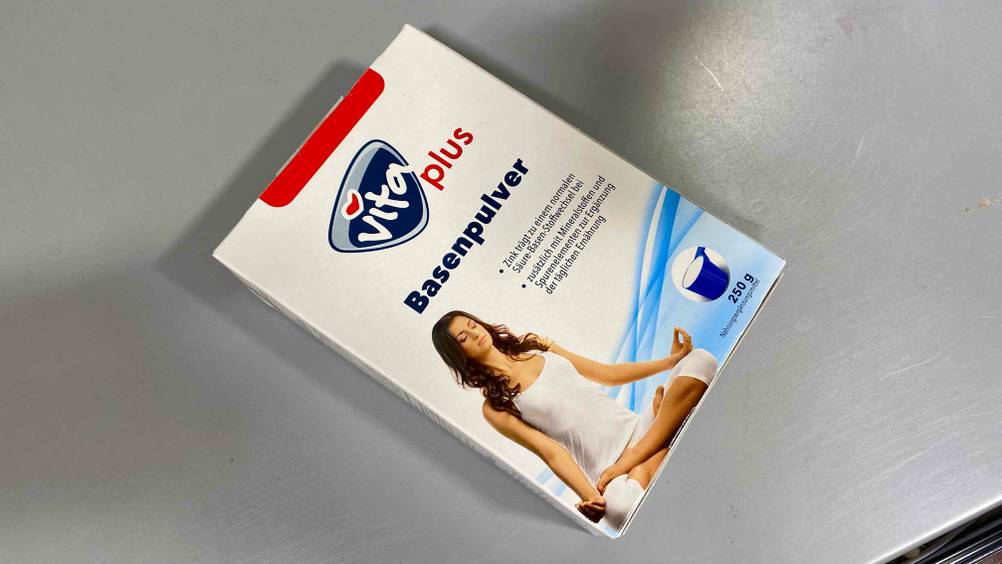 Eine Packung Basenpulver im Test liegt quer auf einer grauen Fläche.