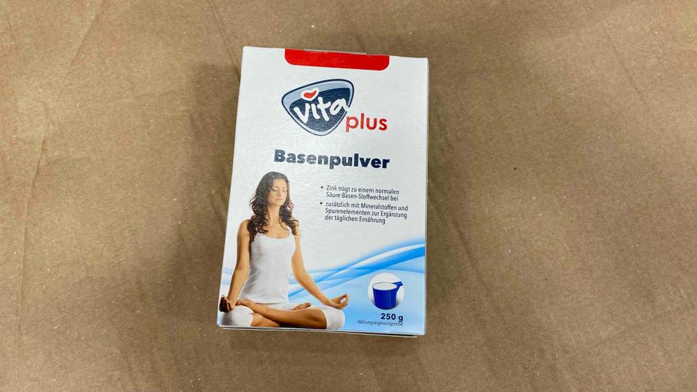 Eine Packung des getesteten Basenpulvers auf einer beigen Fläche liegend.