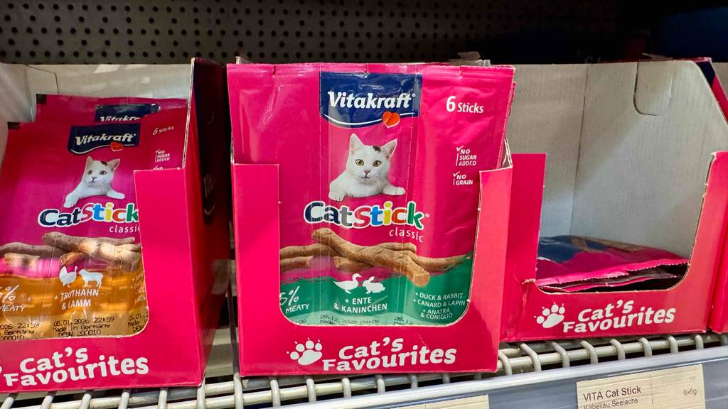 Katzensticks im Test: Mehrere Packungen unterschiedlicher Geschmacksrichtungen stehen in Kartons in einem Regal.